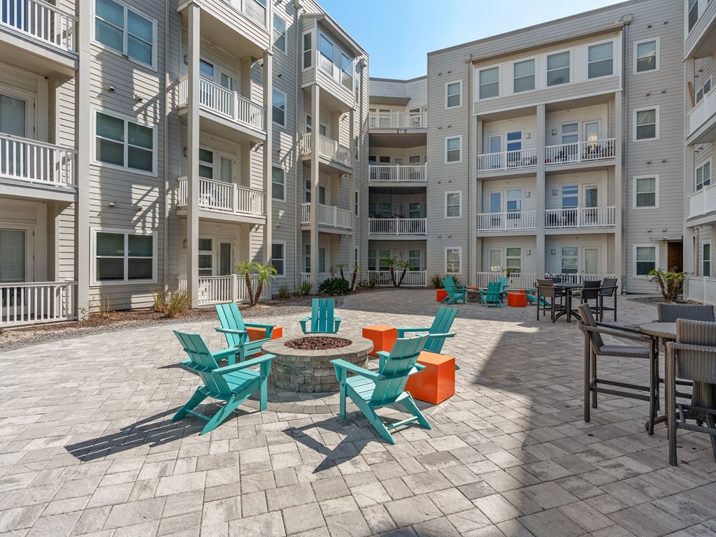 an outdoor patio with chairs and tables in an apartment building at Lake Lofts at Deerwood, Jacksonville, FL, 32216