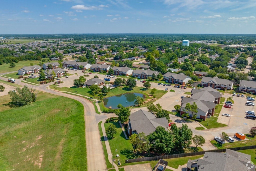 an aerial view of a neighborhood with houses and a pond at Chapel Ridge of Stillwater, Stillwater, 74075