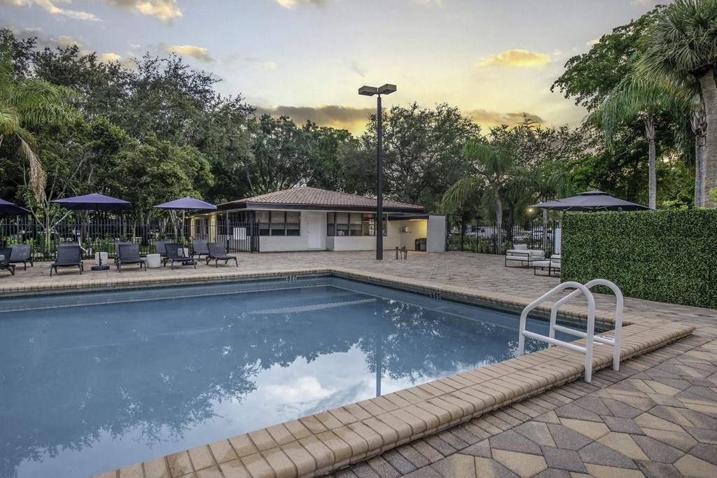 a resort style pool with lounge chairs and umbrellas  at Club at Emerald Waters, Hollywood, FL