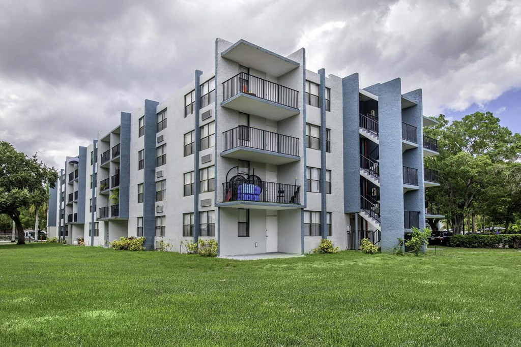 a grey apartment building with a green lawn in front of it  at Club at Emerald Waters, Florida