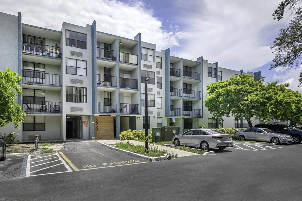 an image of an apartment building with a parking lot in front of it  at Club at Emerald Waters, Hollywood, FL