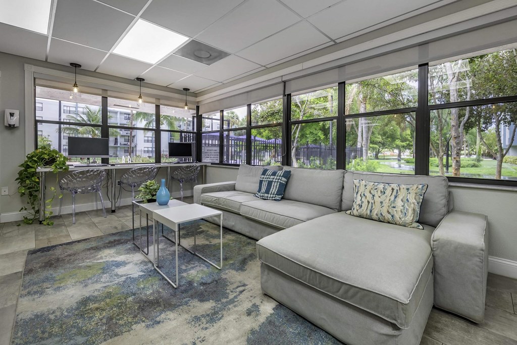 a living room with a couch and a coffee table in front of a wall of windows  at Club at Emerald Waters, Hollywood