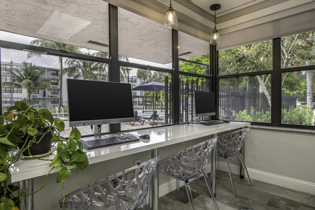 two computer monitors on a long desk in front of a window  at Club at Emerald Waters, Florida