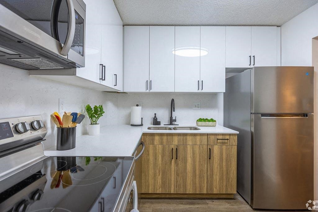 a modern kitchen with white cabinets and stainless steel appliances  at Club at Emerald Waters, Hollywood, Florida