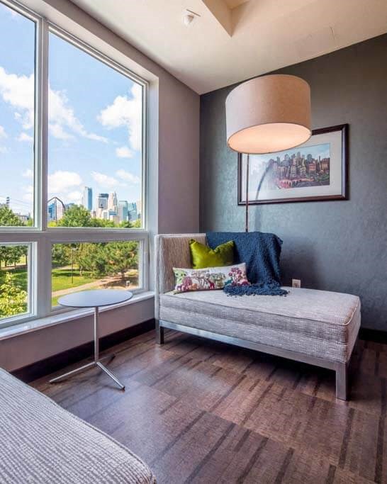 a room with a large window and a chaise lounge