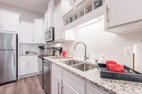 A kitchen with white cabinets and a granite countertop.