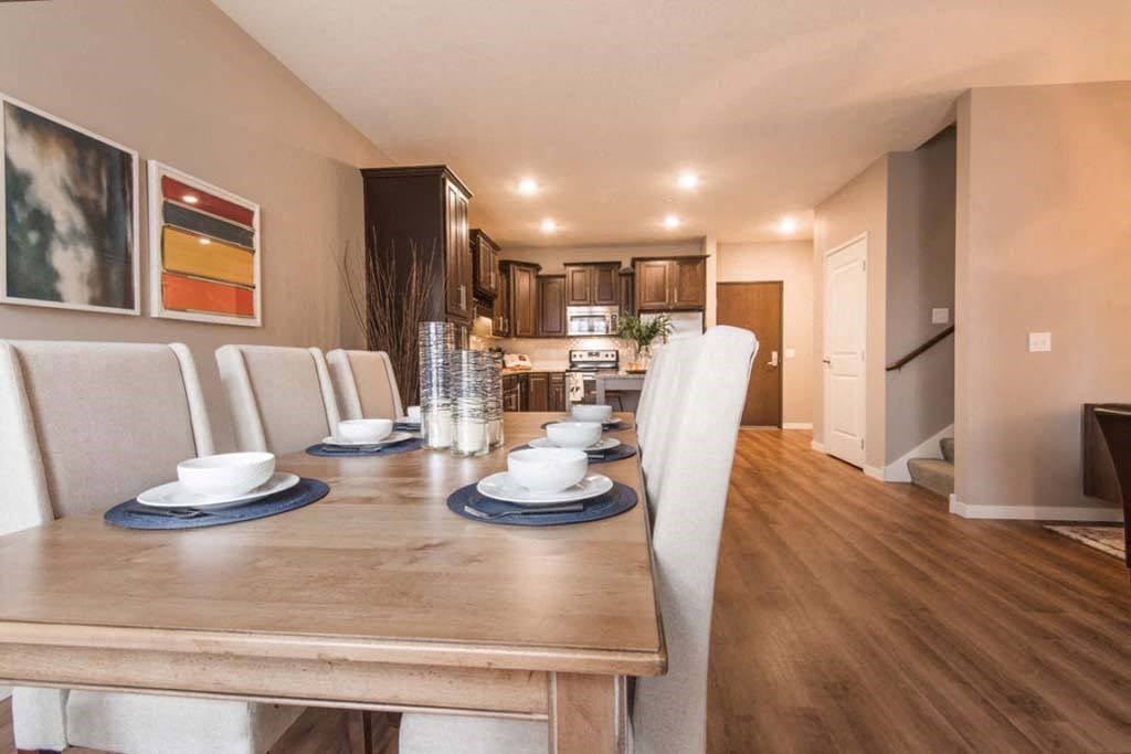 a dining room with a table and chairs and a kitchen in the background