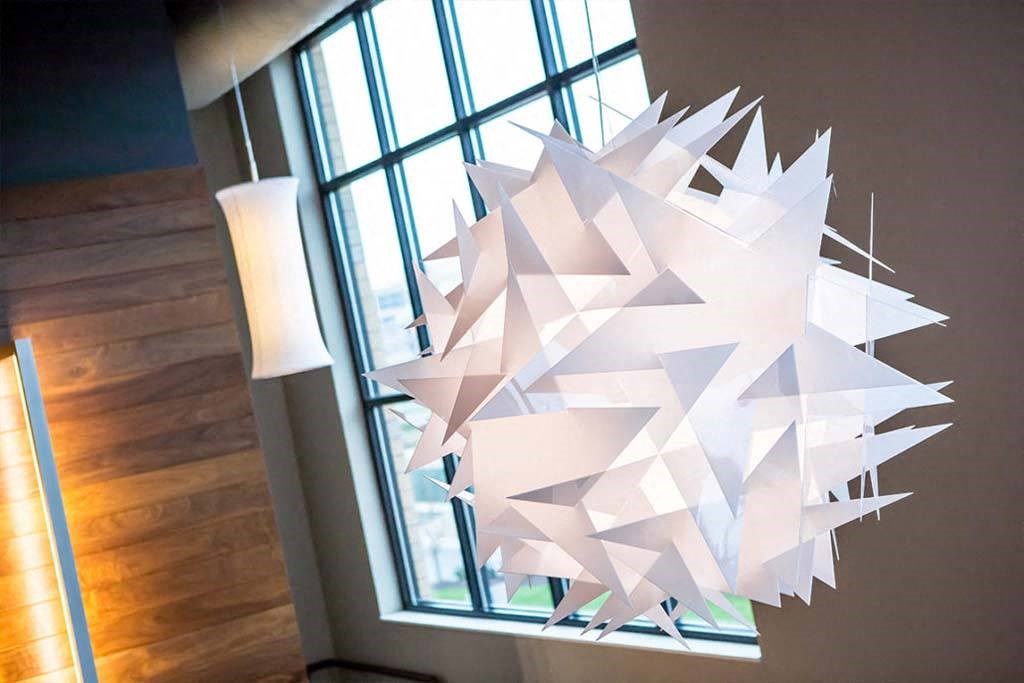 a white paper sculpture hanging from a ceiling next to a window