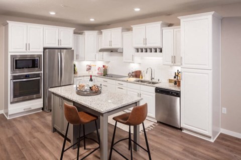 A kitchen with white cabinets and a granite countertop.