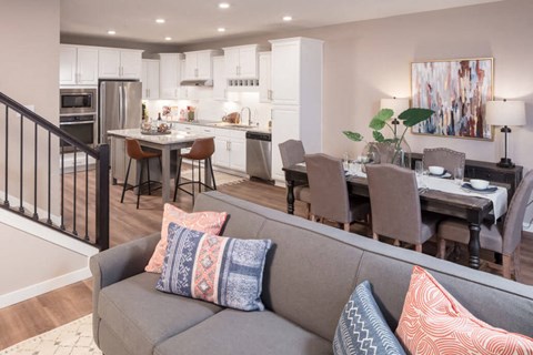 A modern living room with a grey couch and a dining table set up.