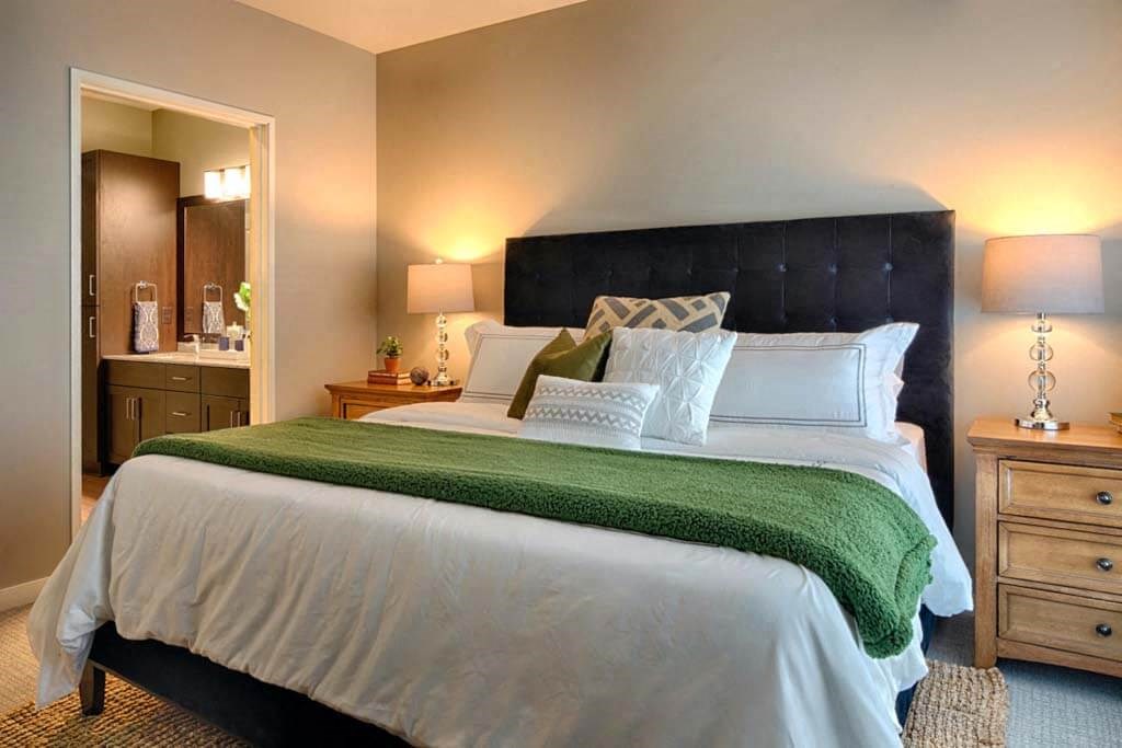 a bedroom with a large bed and a bathroom in the background