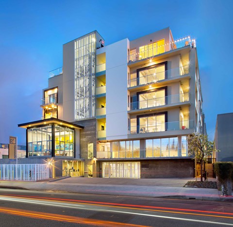 A modern building with a glass facade and a lit up balcony.