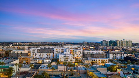 A cityscape at dusk with buildings illuminated and a clear sky.