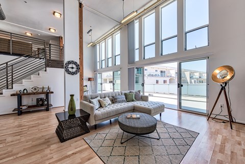 A living room with a couch, a coffee table, and a staircase.