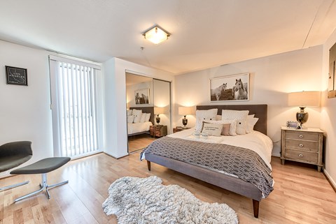 A bedroom with a bed, chair, and a rug.
