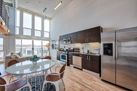 A modern kitchen with a glass table and stainless steel appliances.