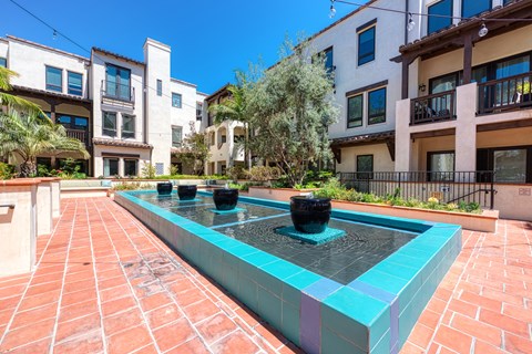 A fountain in the middle of a courtyard surrounded by buildings.