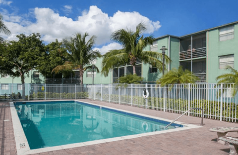 A pool surrounded by a fence and trees.