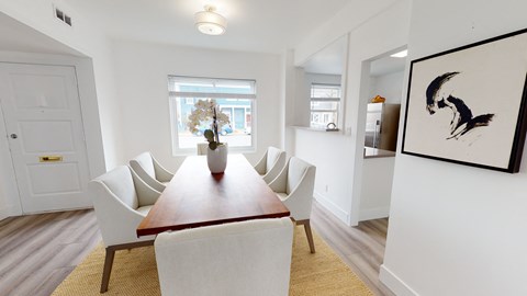 A dining room with a wooden table and white chairs.
