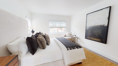 A bedroom with a white bed and a large painting on the wall.