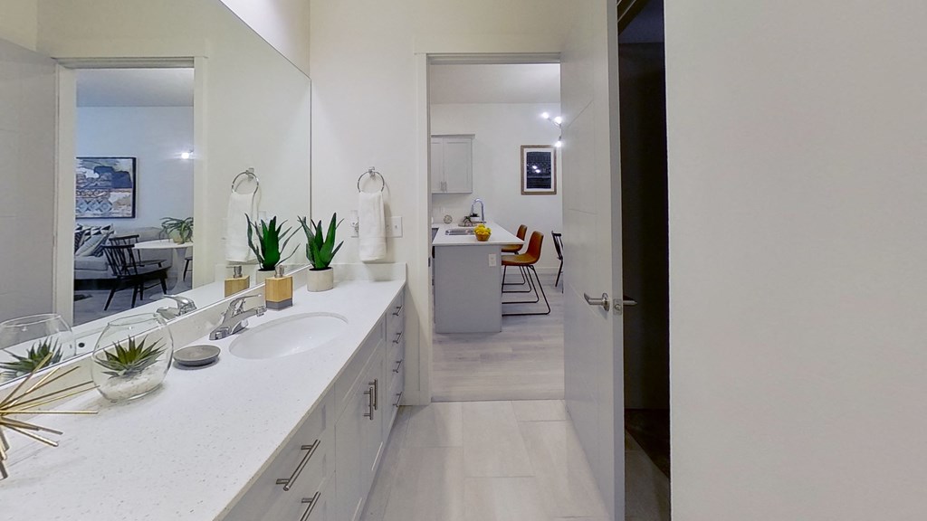 a bathroom with a sink and a mirror and a living room