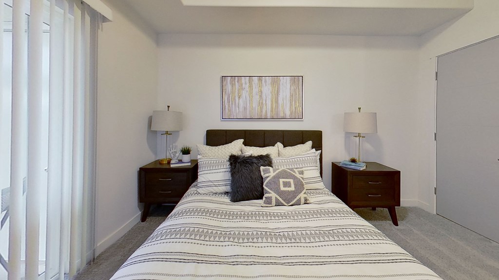 a bedroom with a bed and two nightstands and a window