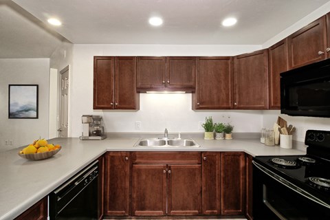 a kitchen with wooden cabinets and black appliances and a sink