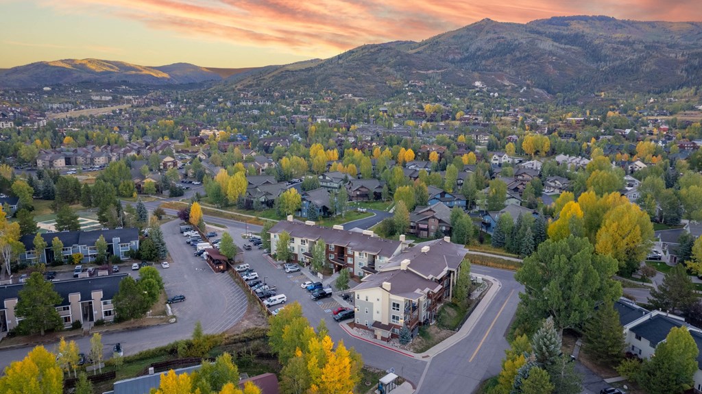 A suburban neighborhood with houses and trees in the foreground and a mountain in the background.