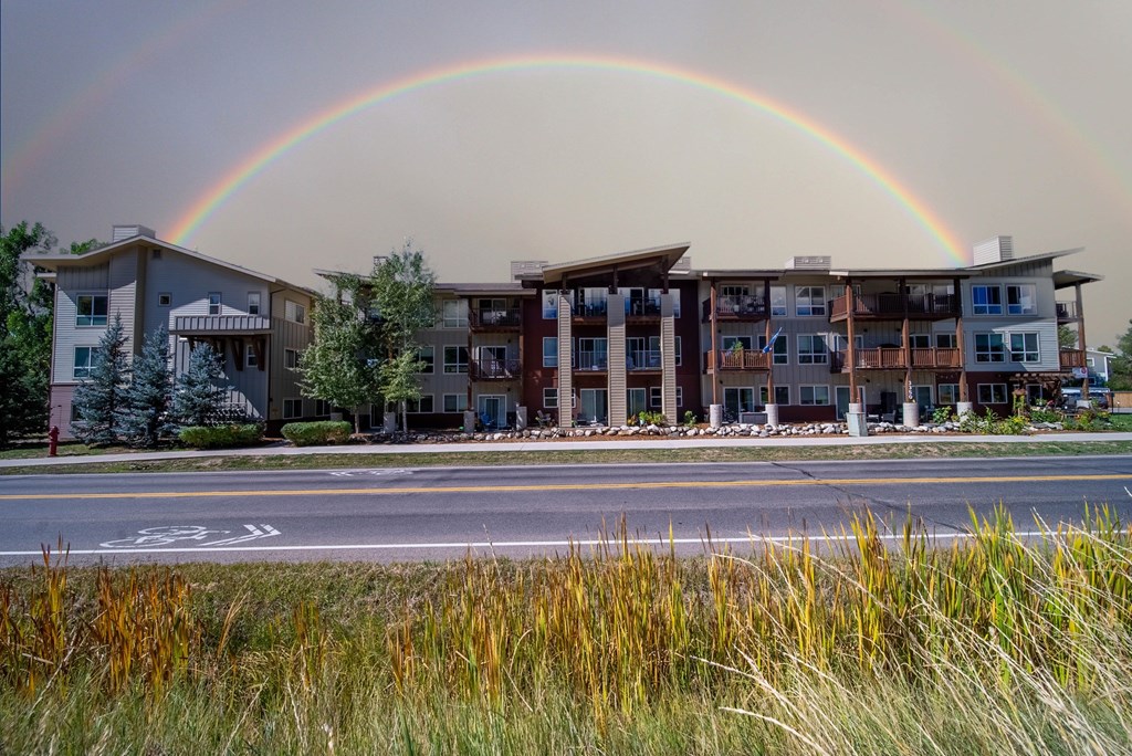 A rainbow appears over a row of townhouses.