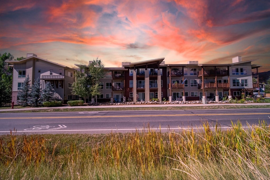 A large apartment complex is shown with a sunset in the background.