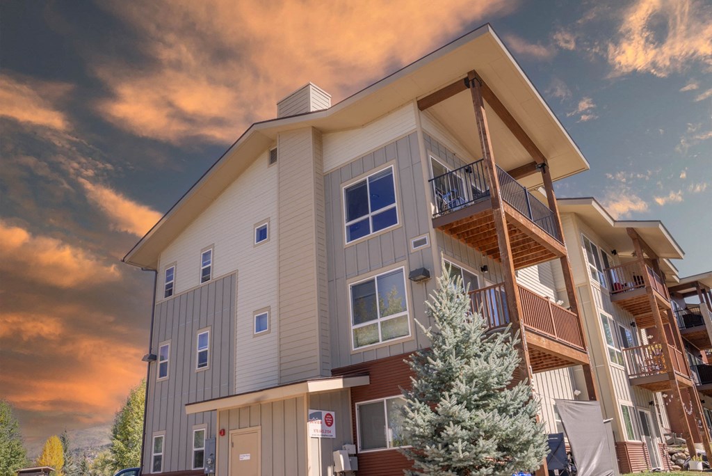 A modern apartment building with balconies and a mountain in the background.