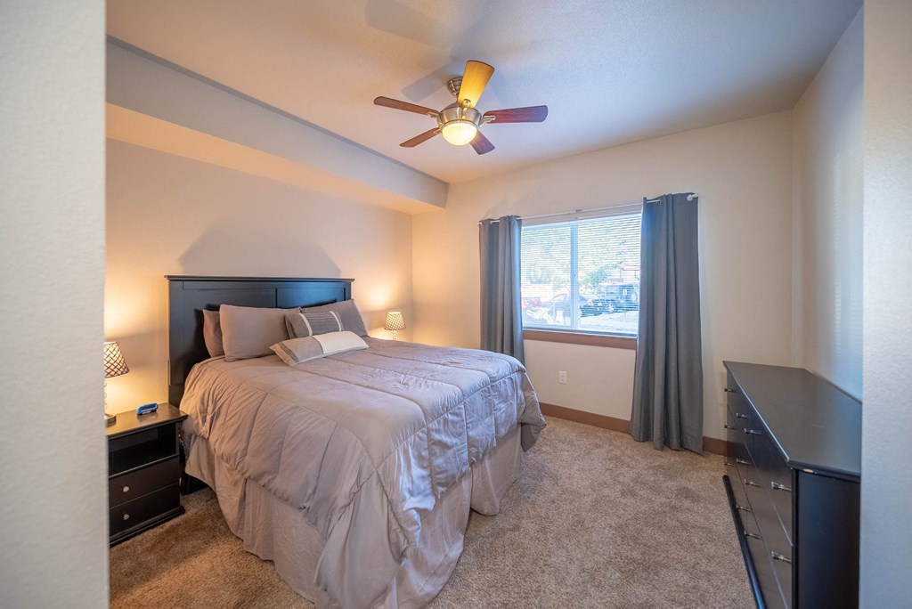 A bedroom with a bed, nightstand, and window.