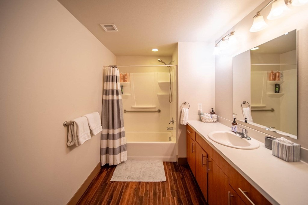 A bathroom with a striped shower curtain and wooden floors.