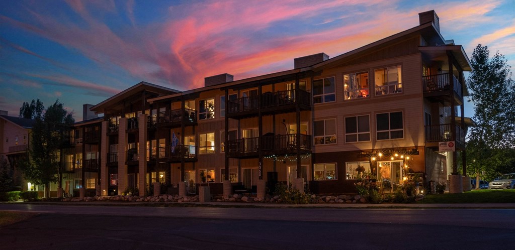 A large apartment building with balconies and lights on.