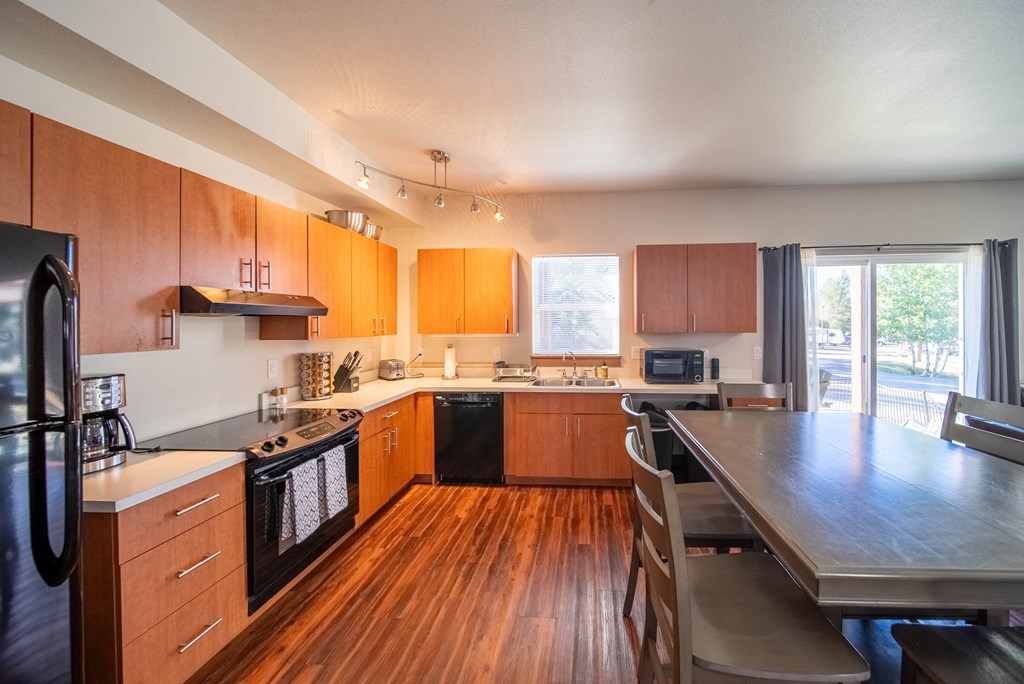 A kitchen with wooden floors and a black refrigerator.