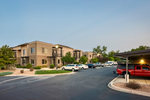 a parking lot with cars parked in front of apartment buildings