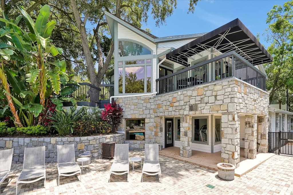 a stone house with a balcony and a patio with chairs