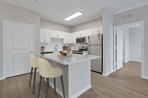 a kitchen with a large island and a stainless steel refrigerator