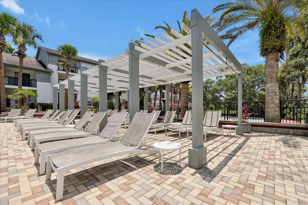 a row of lounge chairs under a canopy on a brick patio