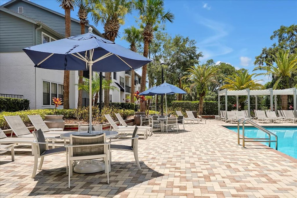 a swimming pool with tables and umbrellas