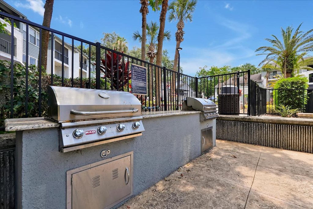 a barbecue grill on the side of a wall with a fence