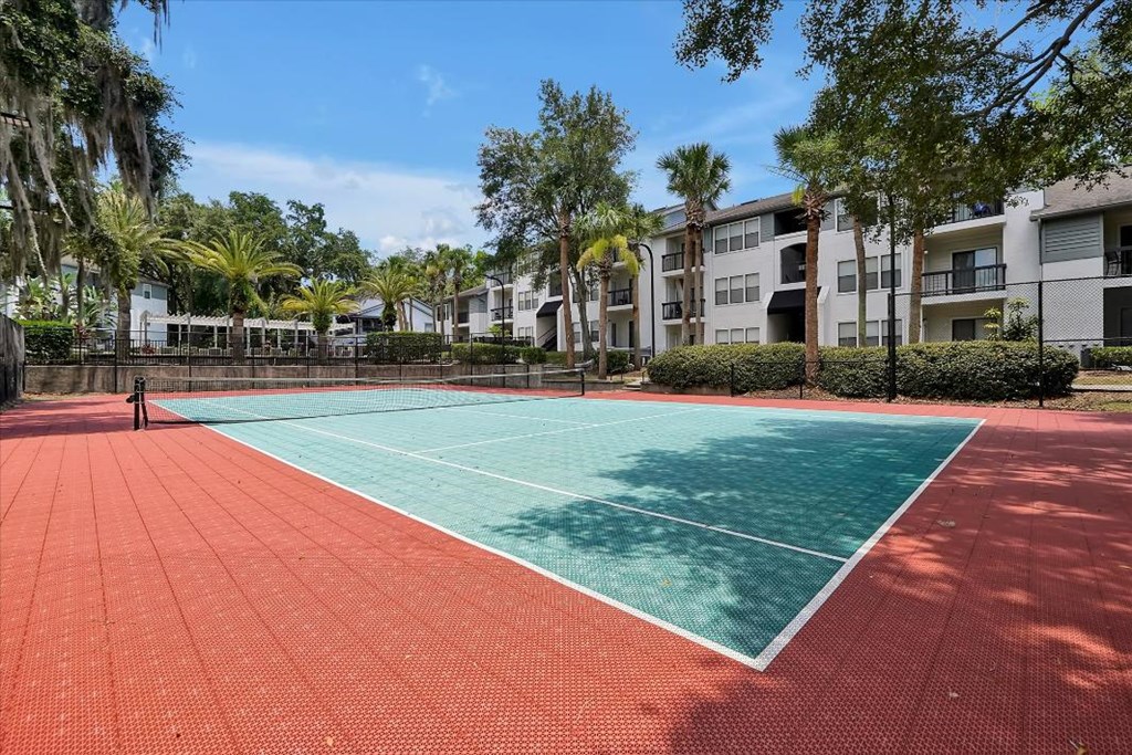 a tennis court with apartments in the background