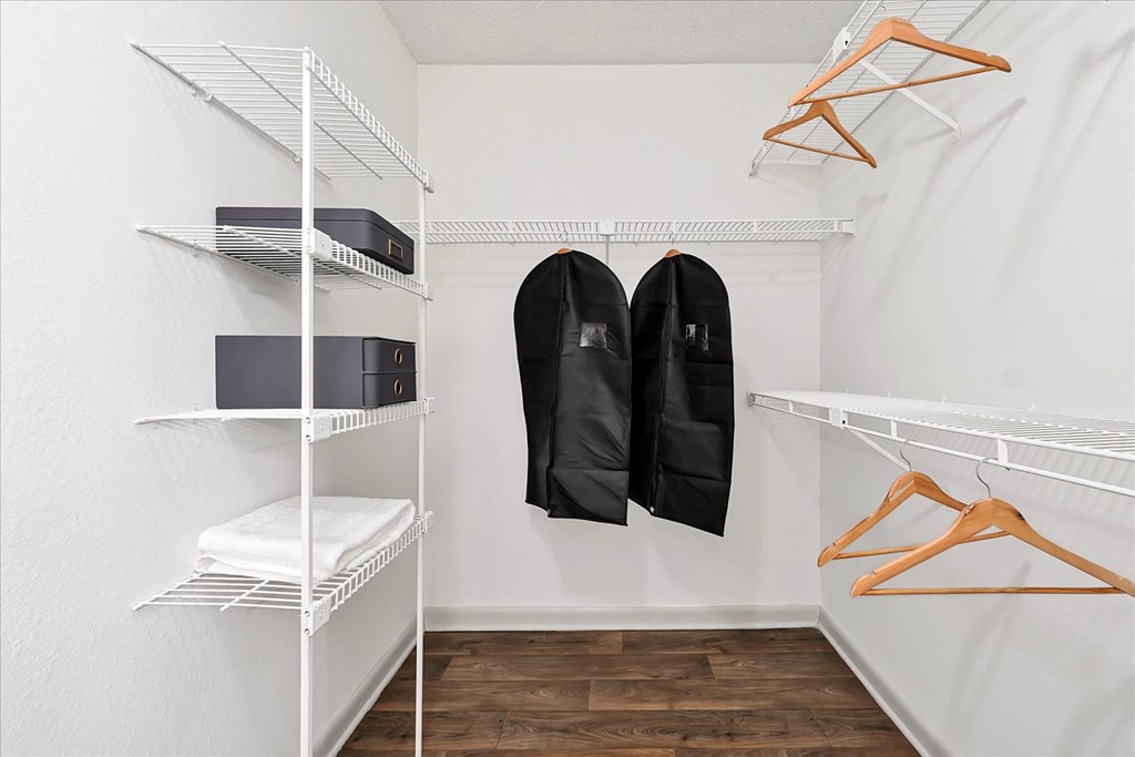 a white closet with a pair of black jackets hanging on the wall