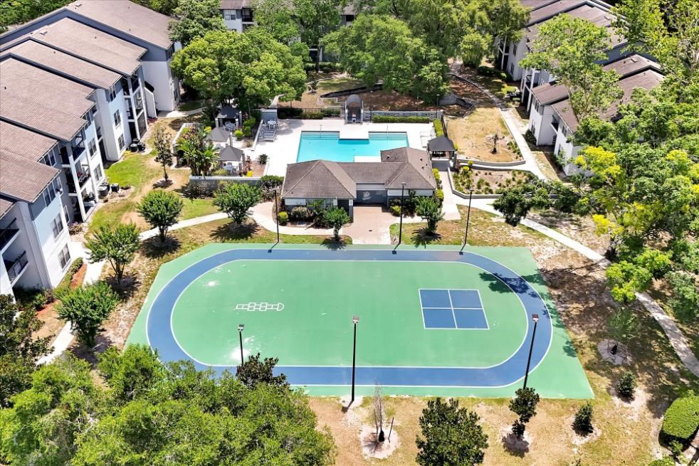 an aerial view of a tennis court in front of a house