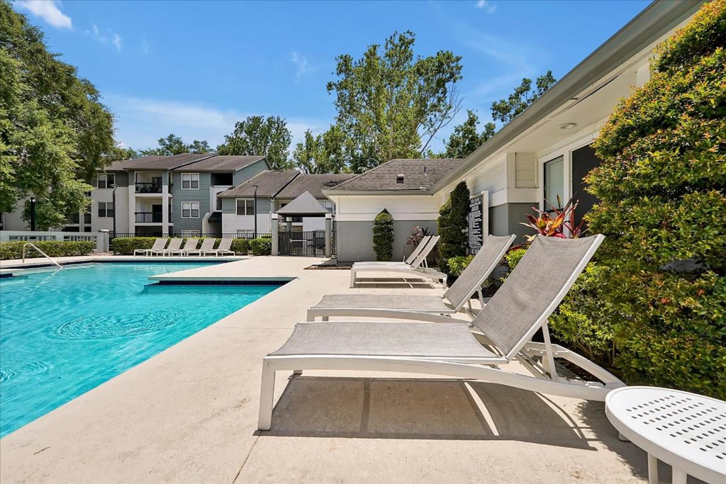 a swimming pool with lounge chairs next to a building