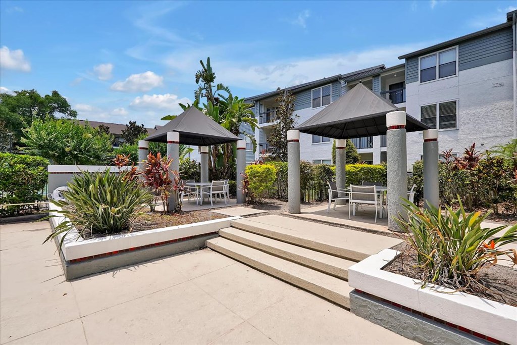 a patio with benches and umbrellas in front of a building