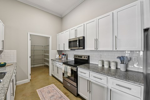 A kitchen with white cabinets and a black stove top oven.