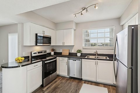 A modern kitchen with white cabinets and stainless steel appliances.