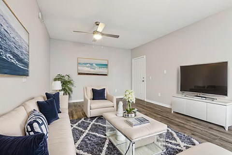 A living room with a white couch, a coffee table, and a painting on the wall.