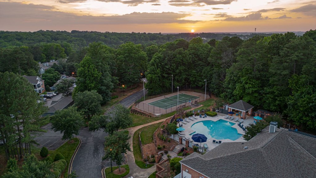 an aerial view of a swimming pool and tennis court at sunset